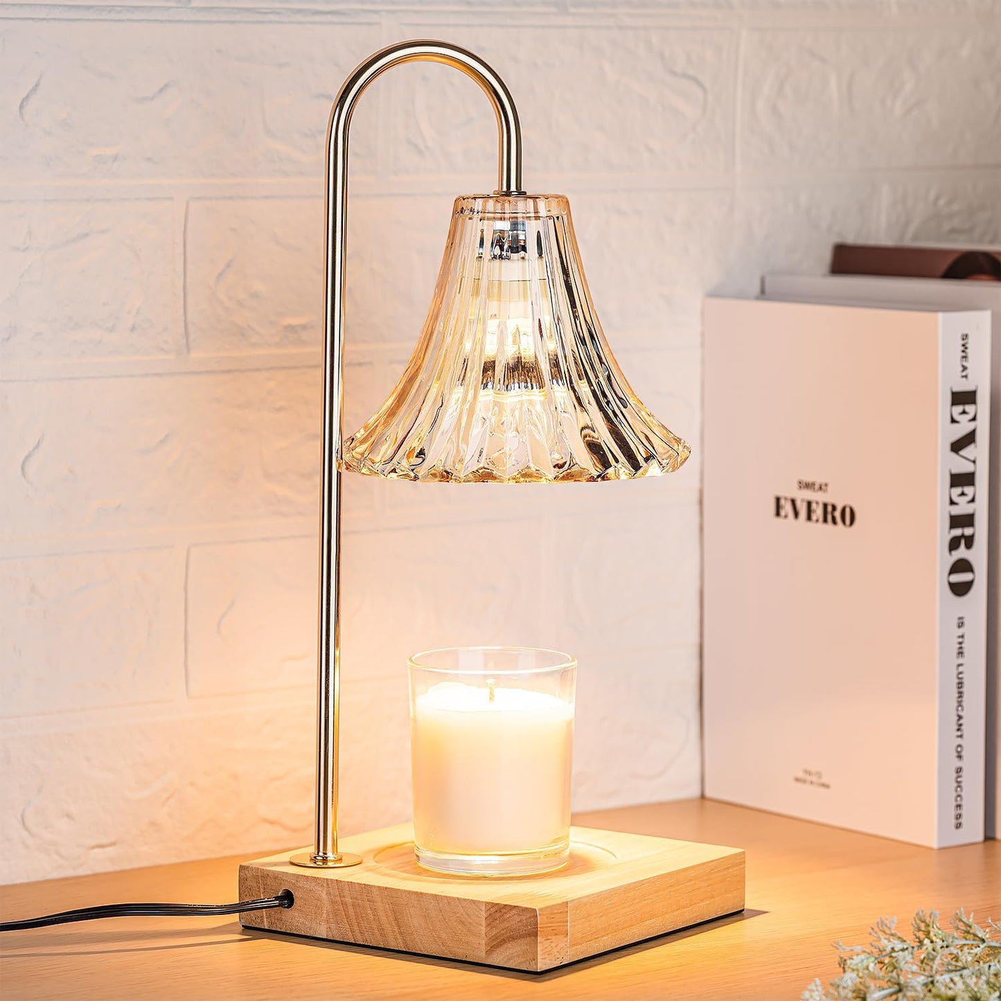 Gold candle warmer lamp on a shelf beside books
