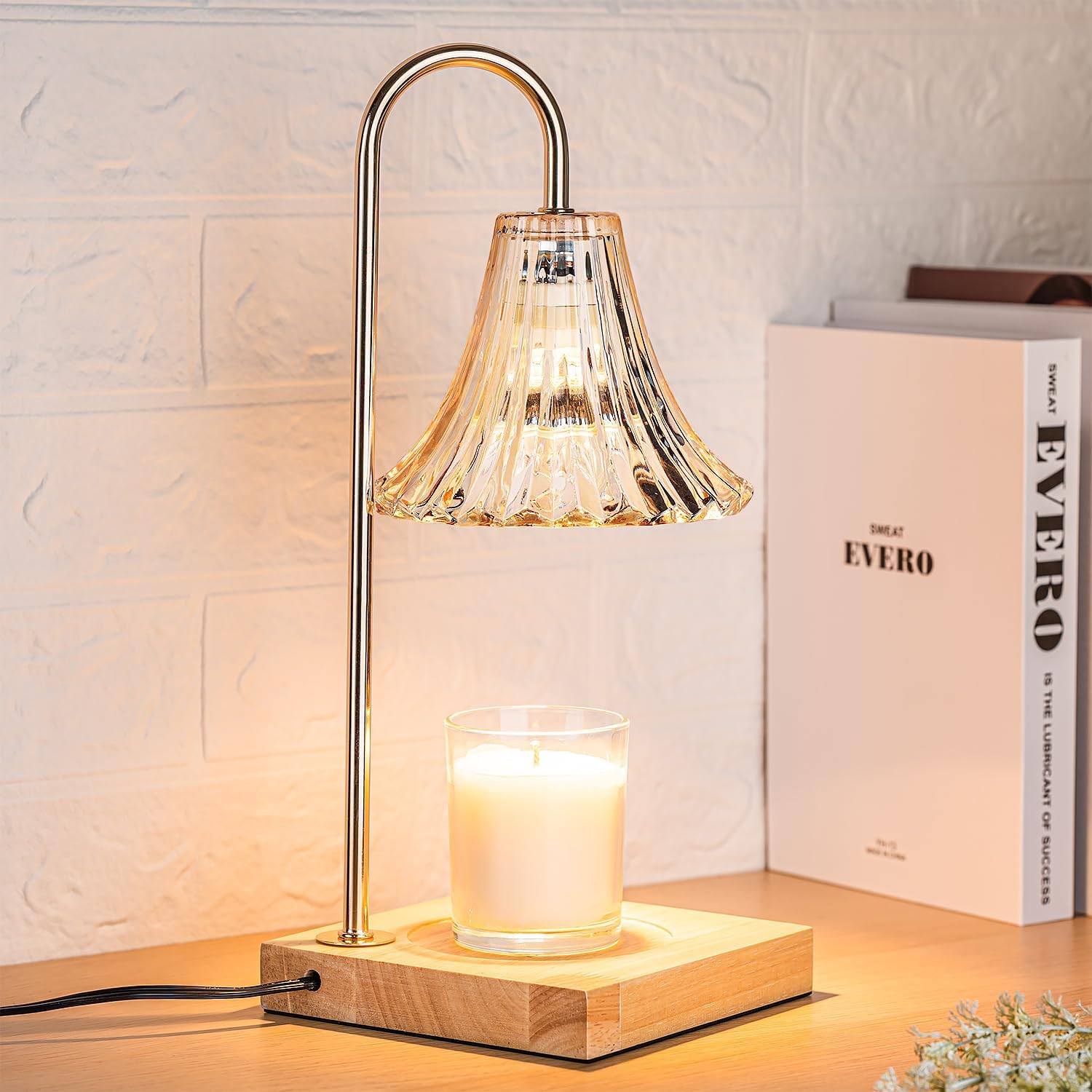 Gold candle warmer lamp on a shelf beside books